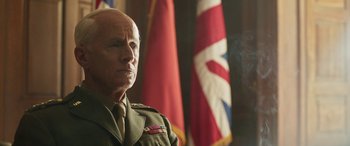 Movie still from “Churchill” (2017), directed by Jonathan Teplitzky – An older man wearing a uniform in front of flags; Close Up shot, Low angle