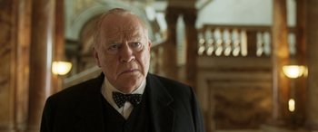 Movie still from “Churchill” (2017), directed by Jonathan Teplitzky – An older man in a suit and bow tie; Close Up shot, Low angle