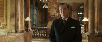 Movie still from “Churchill” (2017), directed by Jonathan Teplitzky – A man in a suit and tie standing in front of a building; Medium shot, Low angle