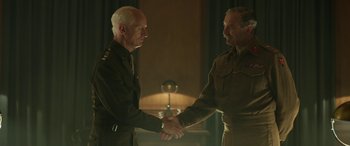 Movie still from “Churchill” (2017), directed by Jonathan Teplitzky – Two men in uniform shaking hands in a room; Medium shot, Over the shoulder angle