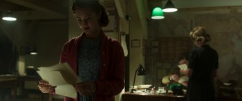 Movie still from “Churchill” (2017), directed by Jonathan Teplitzky – A woman standing in front of a desk holding papers; Medium shot, Over the shoulder angle