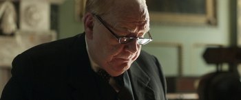 Movie still from “Churchill” (2017), directed by Jonathan Teplitzky – An older man wearing glasses and a suit and tie; Close Up shot, Low angle