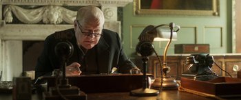 Movie still from “Churchill” (2017), directed by Jonathan Teplitzky – An older man sitting in front of a desk; Close Up shot, Low angle