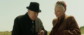 Movie still from “Churchill” (2017), directed by Jonathan Teplitzky – An older man wearing a hat and a woman wearing a coat; Close Up shot, Over the shoulder angle