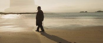 Movie still from “Churchill” (2017), directed by Jonathan Teplitzky – An old man walking on the beach with a cane; Wide shot, Low angle