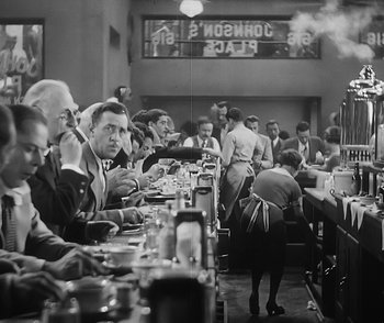 Movie still from “City Girl” (1930), directed by F.W. Murnau – A black and white photo of people sitting at a table; Medium shot, High angle