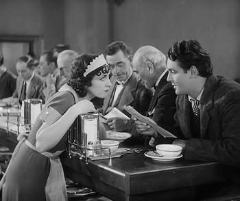Movie still from “City Girl” (1930), directed by F.W. Murnau – An old black and white photo of a group of people sitting at a table; Medium shot, High angle