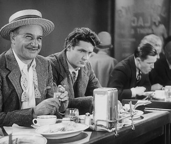 Movie still from “City Girl” (1930), directed by F.W. Murnau – A group of men sitting at a table with plates of food; Medium shot, Over the shoulder angle