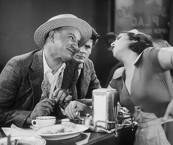 Movie still from “City Girl” (1930), directed by F.W. Murnau – A man and a woman sitting at a table with a plate of food in front of them; Medium shot, Over the shoulder angle