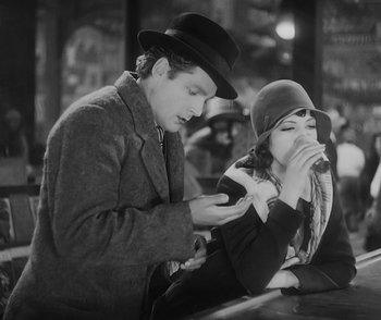 Movie still from “City Girl” (1930), directed by F.W. Murnau – A man and a woman sitting at a table looking at a cell phone; Medium shot, High angle