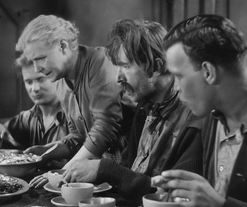 Movie still from “City Girl” (1930), directed by F.W. Murnau – A black and white photo of a group of men sitting at a table; Medium shot, Over the shoulder angle