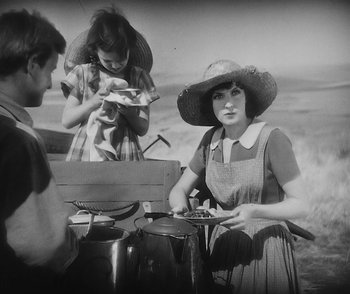 Movie still from “City Girl” (1930), directed by F.W. Murnau – A woman wearing a hat is cooking a meal; Medium shot, High angle