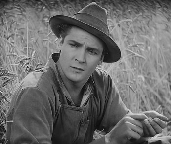 Movie still from “City Girl” (1930), directed by F.W. Murnau – A man wearing an overalls and a hat is sitting in a field; Close Up shot, Low angle