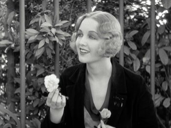 Movie still from “City Lights” (1931), directed by Charles Chaplin – An old photo of a woman holding a flower; Close Up shot, High angle