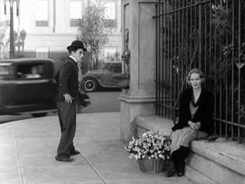 Movie still from “City Lights” (1931), directed by Charles Chaplin – A man and a woman sitting on a bench; Wide shot, High angle