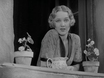 Movie still from “City Lights” (1931), directed by Charles Chaplin – A black - and - white photo of a woman sitting at a table; Medium shot, Low angle