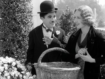 Movie still from “City Lights” (1931), directed by Charles Chaplin – A man and a woman standing next to each other; Medium shot, Over the shoulder angle