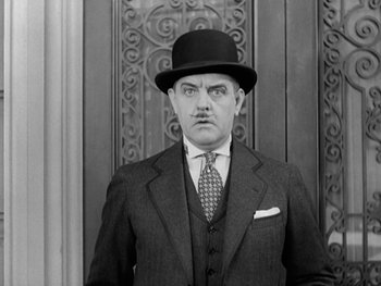 Movie still from “City Lights” (1931), directed by Charles Chaplin – A man wearing a suit and a top hat; Close Up shot, Low angle