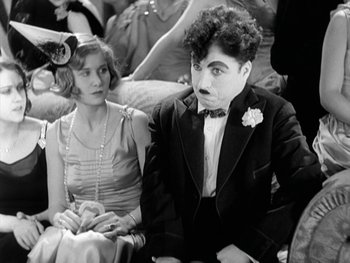 Movie still from “City Lights” (1931), directed by Charles Chaplin – A man and a woman sitting next to each other; Medium shot, Over the shoulder angle