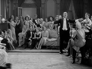 Movie still from “City Lights” (1931), directed by Charles Chaplin – A group of people sitting and standing in a living room; Wide shot, High angle