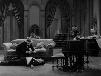Movie still from “City Lights” (1931), directed by Charles Chaplin – A man laying on the floor of a living room next to a piano; Wide shot, High angle