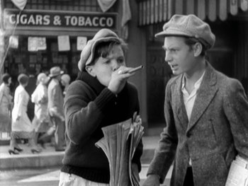 Movie still from “City Lights” (1931), directed by Charles Chaplin – A man and a woman standing next to each other on the sidewalk; Medium shot, High angle