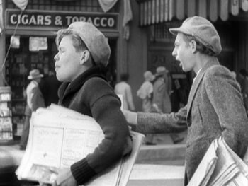 Movie still from “City Lights” (1931), directed by Charles Chaplin – Two men are walking down the street holding newspapers; Medium shot, Low angle