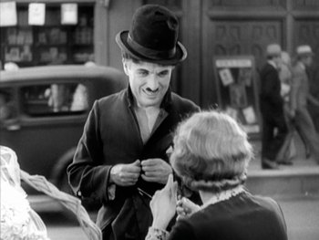 Movie still from “City Lights” (1931), directed by Charles Chaplin – A man in a top hat talking to an older woman; Medium shot, Over the shoulder angle