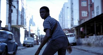 Movie still from “City of God” (2002), directed by Kátia Lund – A man riding a scooter down a street; Medium shot, Low angle
