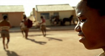 Movie still from “City of God” (2002), directed by Kátia Lund – A man standing on a dirt road near a building; Close Up shot, Low angle