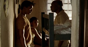 Movie still from “City of God” (2002), directed by Kátia Lund – Two men and a woman standing next to each other in front of a bed; Medium shot, Low angle