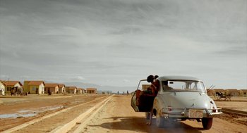 Movie still from “City of God” (2002), directed by Kátia Lund – A woman standing in the back of an old car; Extreme Wide shot, Low angle