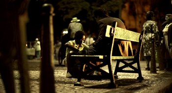 Movie still from “City of God” (2002), directed by Kátia Lund – Two people sitting on a bench in the dark; Wide shot, Over the shoulder angle