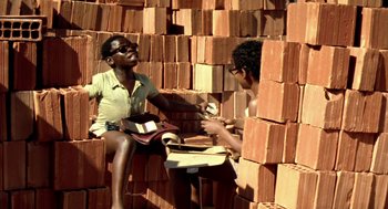 Movie still from “City of God” (2002), directed by Kátia Lund – Two people sitting on a pile of bricks; Medium shot, Low angle