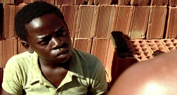 Movie still from “City of God” (2002), directed by Kátia Lund – A man in a green shirt is looking at the camera; Close Up shot, High angle