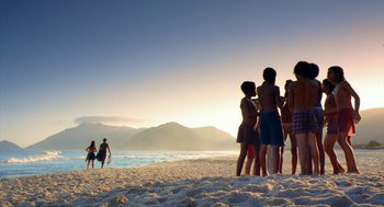 Movie still from “City of God” (2002), directed by Kátia Lund – A group of people standing on top of a sandy beach; Extreme Wide shot, Low angle