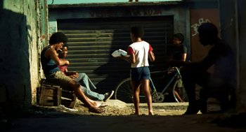 Movie still from “City of God” (2002), directed by Kátia Lund – A group of people sitting on the side of a road; Wide shot, Low angle
