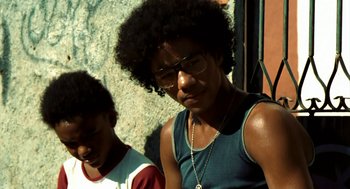 Movie still from “City of God” (2002), directed by Kátia Lund – A young man wearing glasses and a blue shirt; Close Up shot, Low angle