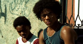 Movie still from “City of God” (2002), directed by Kátia Lund – Two young men standing next to each other in front of a stone wall; Close Up shot, Low angle