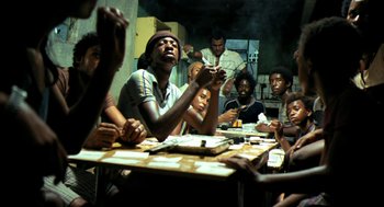 Movie still from “City of God” (2002), directed by Kátia Lund – A group of people sitting around a table; Medium shot, High angle