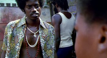 Movie still from “City of God” (2002), directed by Kátia Lund – A man with a beard is standing in front of two other men; Close Up shot, Low angle