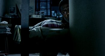Movie still from “City of God” (2002), directed by Kátia Lund – A man is hiding behind a wall in the dark; Medium shot, Overhead angle