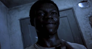 Movie still from “City of God” (2002), directed by Kátia Lund – A man's face in a dark room; Close Up shot, Low angle