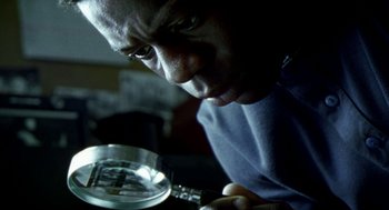 Movie still from “City of God” (2002), directed by Kátia Lund – A person looking at something in a magnifying glass; Extreme Close Up shot, High angle