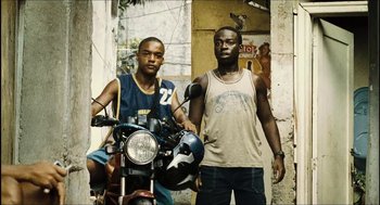 Movie still from “City of Men” (2007), directed by Paulo Morelli – Two young men standing next to each other on a motorcycle; Medium shot, Low angle
