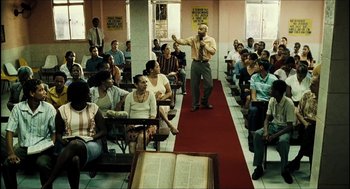 Movie still from “City of Men” (2007), directed by Paulo Morelli – A group of people sitting and standing in a room; Wide shot, High angle