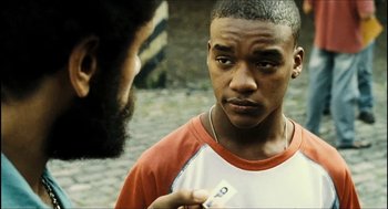 Movie still from “City of Men” (2007), directed by Paulo Morelli – A young black man holding a cell phone in front of a bearded man; Close Up shot, Over the shoulder angle
