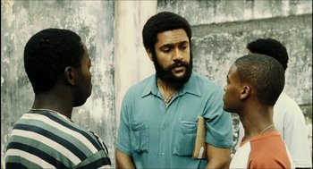 Movie still from “City of Men” (2007), directed by Paulo Morelli – A man with a beard talking to two other men; Medium shot, High angle