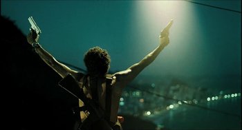 Movie still from “City of Men” (2007), directed by Paulo Morelli – A man holding a gun in the air with his arm raised; Medium shot, Low angle
