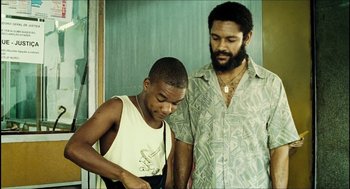 Movie still from “City of Men” (2007), directed by Paulo Morelli – A man standing next to a young boy; Medium shot, Low angle